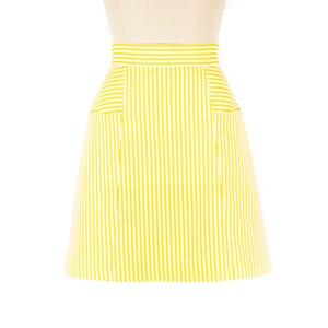 May include: A yellow and white striped skirt with two pockets on the front.