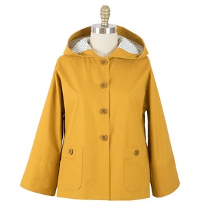 May include: A mustard yellow hooded jacket with a white polka dot lining and brown buttons.