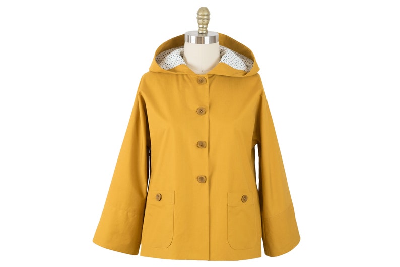 May include: A mustard yellow hooded jacket with a white polka dot lining and brown buttons.