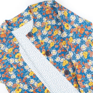 May include: A blue floral fabric with a white polka dot lining. The fabric features a variety of flowers in shades of yellow, orange, and white.