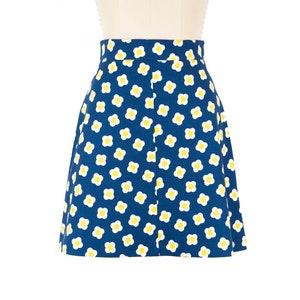 May include: A blue skirt with a white and yellow daisy print.