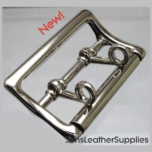 May include: A silver-toned metal buckle with a rectangular frame and a sliding bar. The buckle has two small loops on the side. The buckle is new.