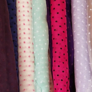 May include: Five rolls of sheer fabric with polka dots. The fabrics are in the colors purple, pink, light blue, hot pink, and light purple.