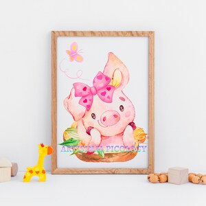 May include: A watercolor illustration of a pink pig with a pink bow, sitting in a nest of leaves. A pink butterfly flies above the pig. The illustration is framed in a light brown wooden frame.
