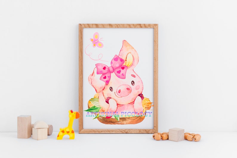 May include: A watercolor illustration of a pink pig with a pink bow, sitting in a nest of leaves. A pink butterfly flies above the pig. The illustration is framed in a light brown wooden frame.