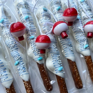 May include: Pretzel rods dipped in white chocolate, decorated with blue drizzle, sugar pearls, and blue fish-shaped sprinkles. Each pretzel is topped with a red and white bobber and packaged in clear cellophane.