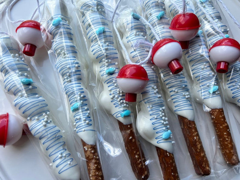 May include: Pretzel rods dipped in white chocolate, decorated with blue squiggles, blue fish candies, and white sprinkles. Each pretzel is packaged in clear cellophane and paired with a red and white bobber. A fun, themed treat.