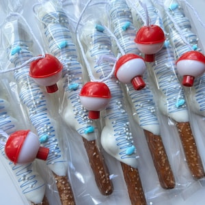 May include: Pretzel rods dipped in white chocolate, decorated with blue lines, fish-shaped sprinkles, and white sprinkles. Each pretzel is packaged in clear cellophane and topped with a red and white bobber. A fun, themed treat.