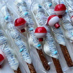 May include: Pretzel rods dipped in white chocolate, decorated with blue lines, fish-shaped sprinkles, and white nonpareils. Each pretzel is packaged and topped with a red and white bobber. A fun, themed treat.