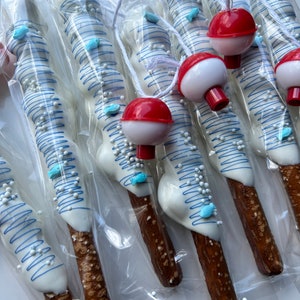 May include: Pretzel rods dipped in white chocolate, decorated with blue drizzle, sprinkles, and blue fish-shaped candies. Each pretzel is packaged in clear cellophane and topped with a red and white bobber.