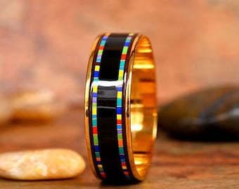 May include: A black and gold bangle bracelet with a colorful geometric pattern. The bracelet is made of metal and has a smooth, polished finish.
