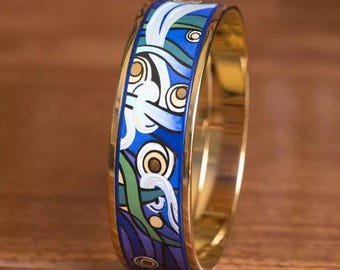 May include: A gold bangle bracelet with a blue and green enamel design featuring stylized waves and circles.