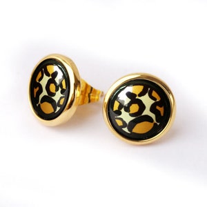 May include: A pair of gold-toned stud earrings with a black and white leopard print design.