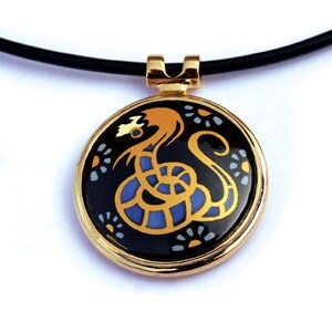 May include: A gold pendant necklace with a black enamel circle featuring a stylized gold and blue dragon design.