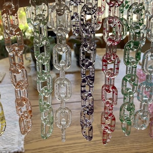 May include: A collection of clear plastic chains with different colored glitter embedded inside. The chains are hanging from a ceiling or a wall.