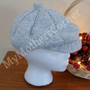 May include: A light blue knitted beret with a textured pattern. The beret is on a white mannequin head.