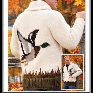 May include: A cream-coloured knit jumper featuring a shawl collar and a large intarsia graphic of a flying mallard duck on the back. The bottom hem is a dark olive green with a jagged brown border. The text reads WHITE BUFFALO Pattern 416 DUCKS.