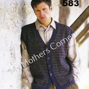 May include: A button-up, dark blue and brown knitted vest with a V-neck, worn over a collared shirt. The vest has a ribbed hem and a blue trim. The number "583" is in the upper right corner. The text "My Mothers Corner" is on the image.