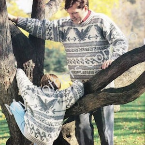 May include: Two people wearing matching sweaters with a geometric pattern and a bird design. The sweaters are white and gray with black accents. The people are standing in front of a tree.