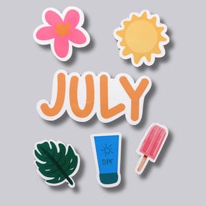 May include: A collection of summer-themed stickers featuring a pink flower, a yellow sun, a green leaf, a blue sunscreen tube with SPF text, a pink popsicle, and the word "JULY" in orange letters.