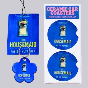 May include: A rectangular air freshener, a flower-shaped keychain, and two round ceramic car coasters featuring the book cover art for The Housemaid by Freida McFadden. Each item displays a blue background, a keyhole graphic with an eye, and text.