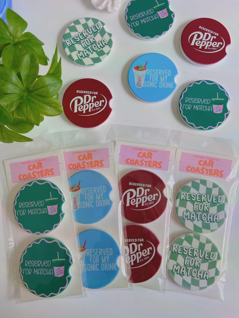 May include: A collection of car coasters featuring text like "Reserved for Matcha" and "Reserved for Dr. Pepper." The coasters are circular, with some having a scalloped edge. They are available in green, red, and blue, and are packaged.