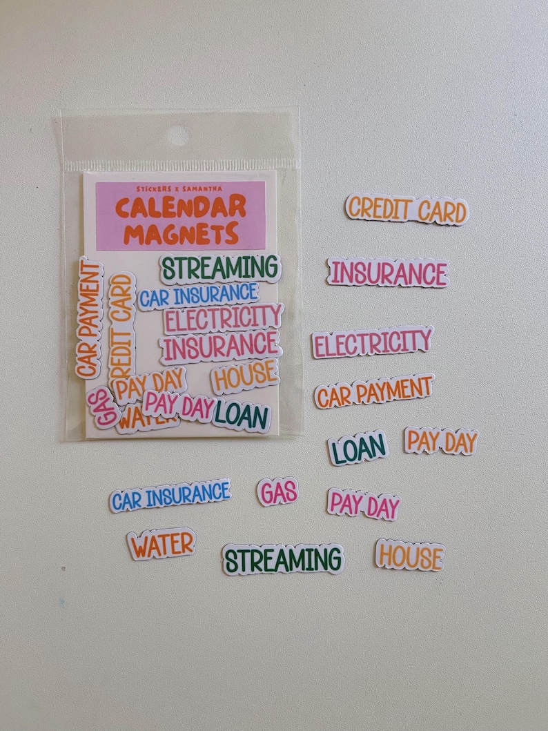 May include: A set of colorful calendar magnets in a clear plastic sleeve, featuring various text labels including Credit Card, Insurance, Electricity, Car Payment, Pay Day, House, Loan, Gas, Water, and Streaming, printed in diverse fonts and colors.