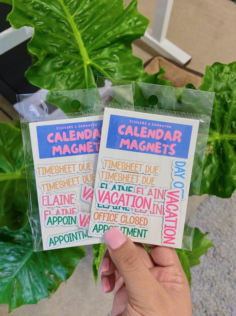 May include: Two identical clear plastic packages containing sets of calendar magnets. Each white backing card features a blue header with the text "STICKERS X SAMANTHA" and "CALENDAR MAGNETS" in pink. The magnets include phrases like "TIMESHEET DUE", "VACATION", "OFFICE CLOSED", "ELAINE", and "APPOINTMENT" in various colors.