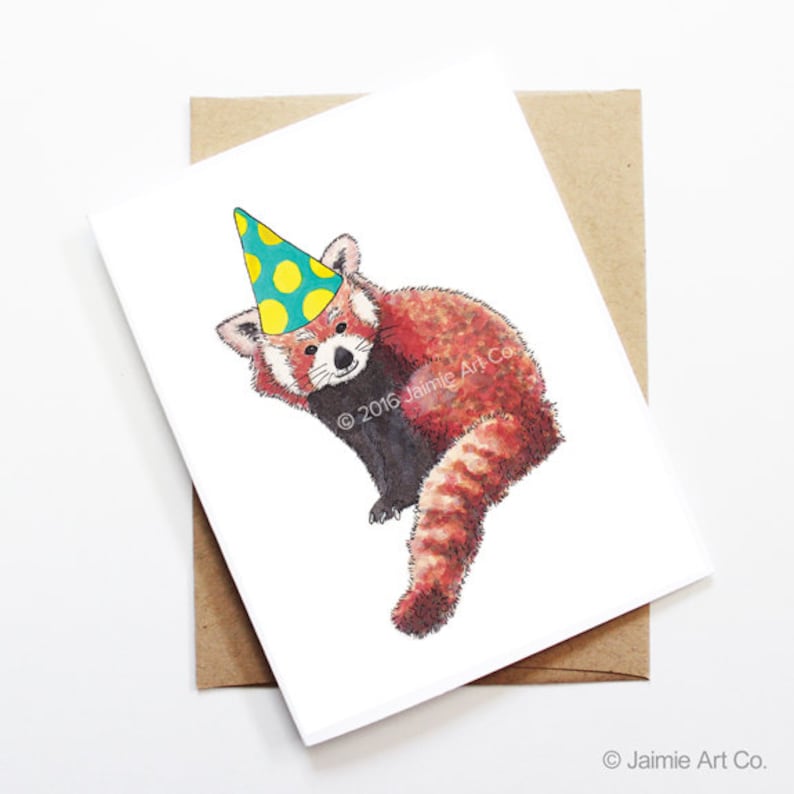 Puede incluir: Una tarjeta de felicitaci&oacute;n blanca con una ilustraci&oacute;n en acuarela de un panda rojo con un gorro de fiesta con lunares amarillos. La tarjeta va acompa&ntilde;ada de un sobre marr&oacute;n. El texto "&copy; 2016 Jaimie Art Co." est&aacute; impreso en la tarjeta.