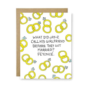 May include: A white greeting card with a repeating pattern of yellow rings and diamond engagement rings. The text in the center reads: WHAT DID JAY-Z CALL HIS GIRLFRIEND BEFORE THEY GOT MARRIED? FEYONC&Eacute;. The card is paired with a brown envelope.