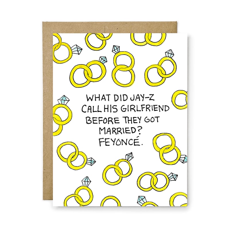 May include: A white greeting card with a repeating pattern of yellow rings and diamond engagement rings. The text in the center reads: WHAT DID JAY-Z CALL HIS GIRLFRIEND BEFORE THEY GOT MARRIED? FEYONC&Eacute;. The card is paired with a brown envelope.