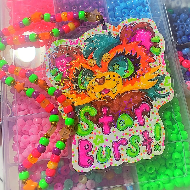 Puede incluir: Un animal de dibujos animados colorido con un fondo rosa, verde y amarillo brillante. El animal tiene ojos grandes y una sonrisa de dientes. El texto "Star Burst!" est&aacute; escrito en letras rosas y verdes.