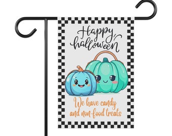 May include: A Halloween garden flag featuring two cartoon pumpkins in shades of blue and teal with smiling faces. The flag has the words "Happy Halloween" and "We have candy and non-food treats" on a white background with a black and white checkered border.