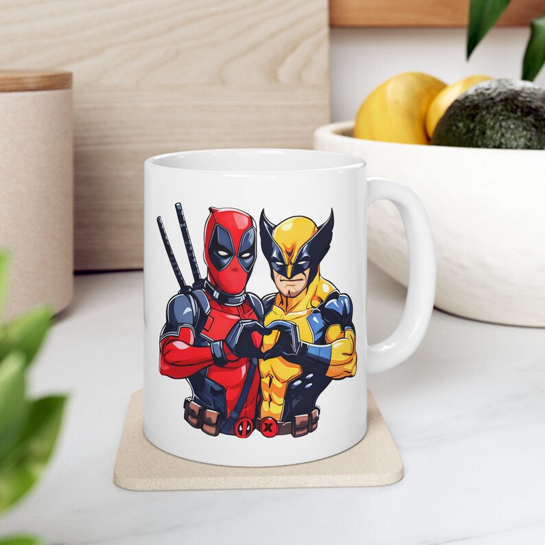 May include: White ceramic mug with a graphic of Deadpool and Wolverine in a heart shape. The mug has a black handle.