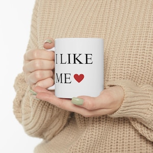 May include: White ceramic mug with black text that reads "I LIKE ME" and a red heart.
