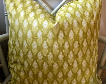 May include: A green and white patterned throw pillow with a diamond pattern. The pillow is sitting on a white chair.