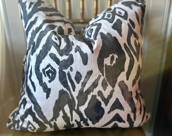 May include: A black and white patterned throw pillow with an abstract design. The pillow is sitting on a gold chair.