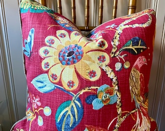 May include: A decorative pillow with a vibrant floral pattern. The pillow features a red background with large yellow and blue flowers, green leaves, and a bird design. The pillow is placed on a gold-colored chair.