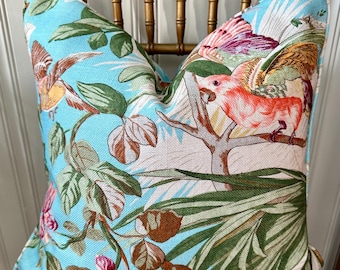 May include: A blue and white throw pillow with a tropical print featuring pink and yellow birds, green leaves, and pink flowers.