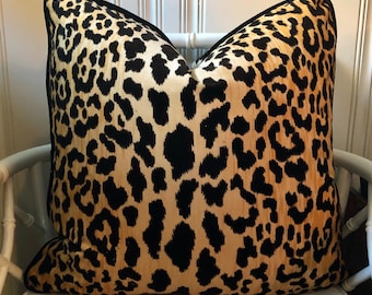 May include: A black and gold leopard print throw pillow with a black trim.