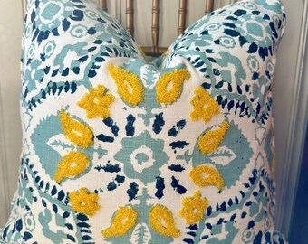 May include: A decorative throw pillow with a white background and a blue and black paisley pattern. The pillow has yellow embroidered details.