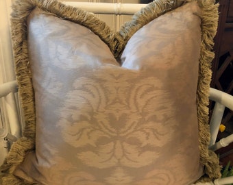 May include: A beige throw pillow with a damask pattern and a brown fringe border.