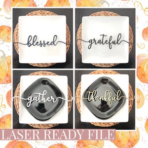 May include: Four laser cut place card holders with the words "blessed", "grateful", "gather", and "thankful" in a cursive font. The place card holders are displayed on white plates with brown woven placemats.