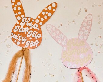 May include: Two pink and orange bunny-shaped paper cutouts with white polka dots and text. The text on the orange bunny says "Hi Hop Hip Hoppy Hop". The text on the pink bunny says "Hi Hoppy Hopity Hop".