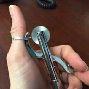 Puede incluir: Una ruleta de sastre de metal plateado con una cuchilla circular dentada unida a un mango. La herramienta está diseñada para marcar patrones en tela o papel, con un acabado metálico y un mecanismo de rueda giratoria en la parte superior.