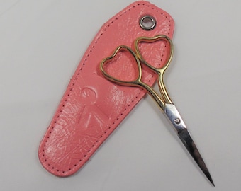 May include: A pink leather case with a gold heart-shaped pair of scissors.