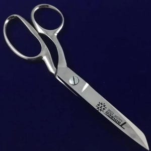 Puede incluir: Tijeras plateadas con mango negro y el texto "RMSCO RAZOR EDGE" en la hoja.