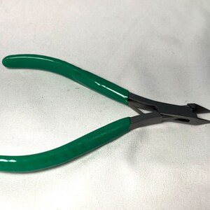 May include: Pliers with green handles and a sharp, angled cutting edge.