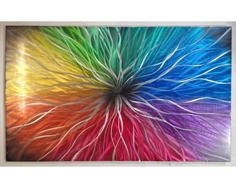 May include: Abstract metal wall art featuring a rainbow color scheme with silver metallic lines radiating from the center. The colors are arranged in a circular pattern, creating a dynamic and eye-catching design.
