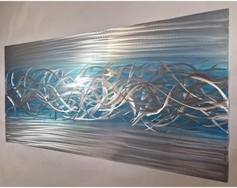 May include: Abstract metal wall art with a blue and silver color scheme. The metal is textured and has a wavy, flowing design.